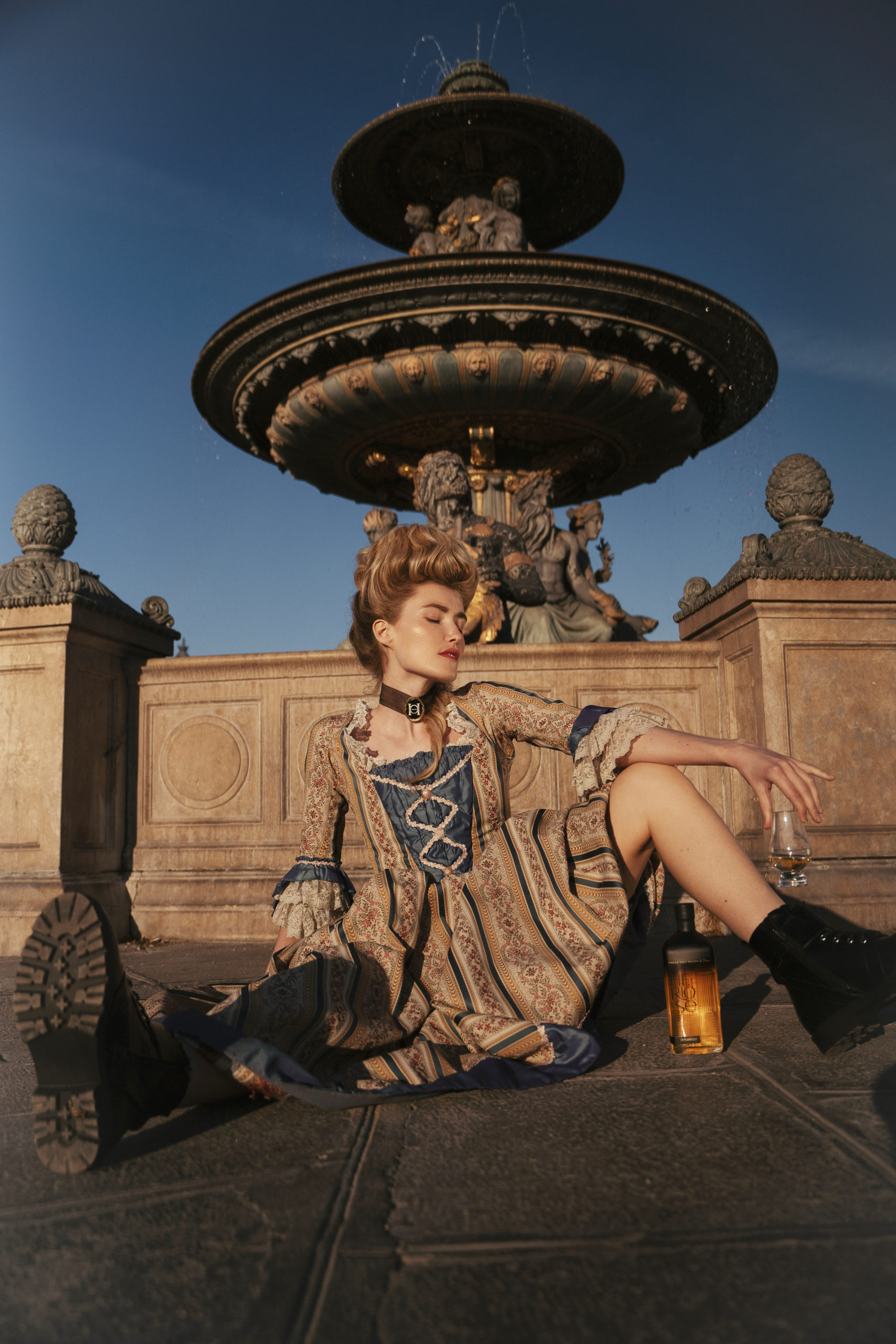 Une Marie-Antoinette des temps modernes. Elle porte une robe d'époque des bottes noires rock. Son maquillage est très glow et frais. Sa coiffure style époque.