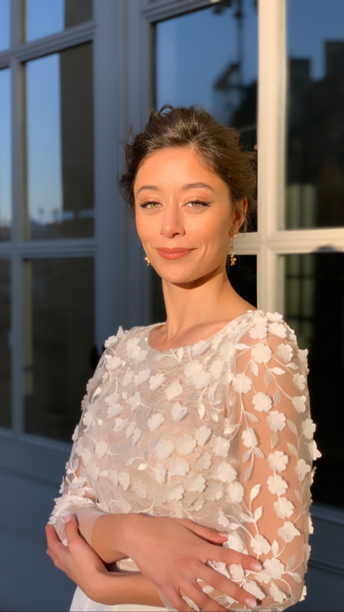 Une mariée brune avec un chignon. Elle porte une tenue de mariage civil moderne et son maquillage est glow naturel mais bien travaillé. Elle a un liner fumé qui dessine son regard sans l'alourdir pour un effet oeil de biche.