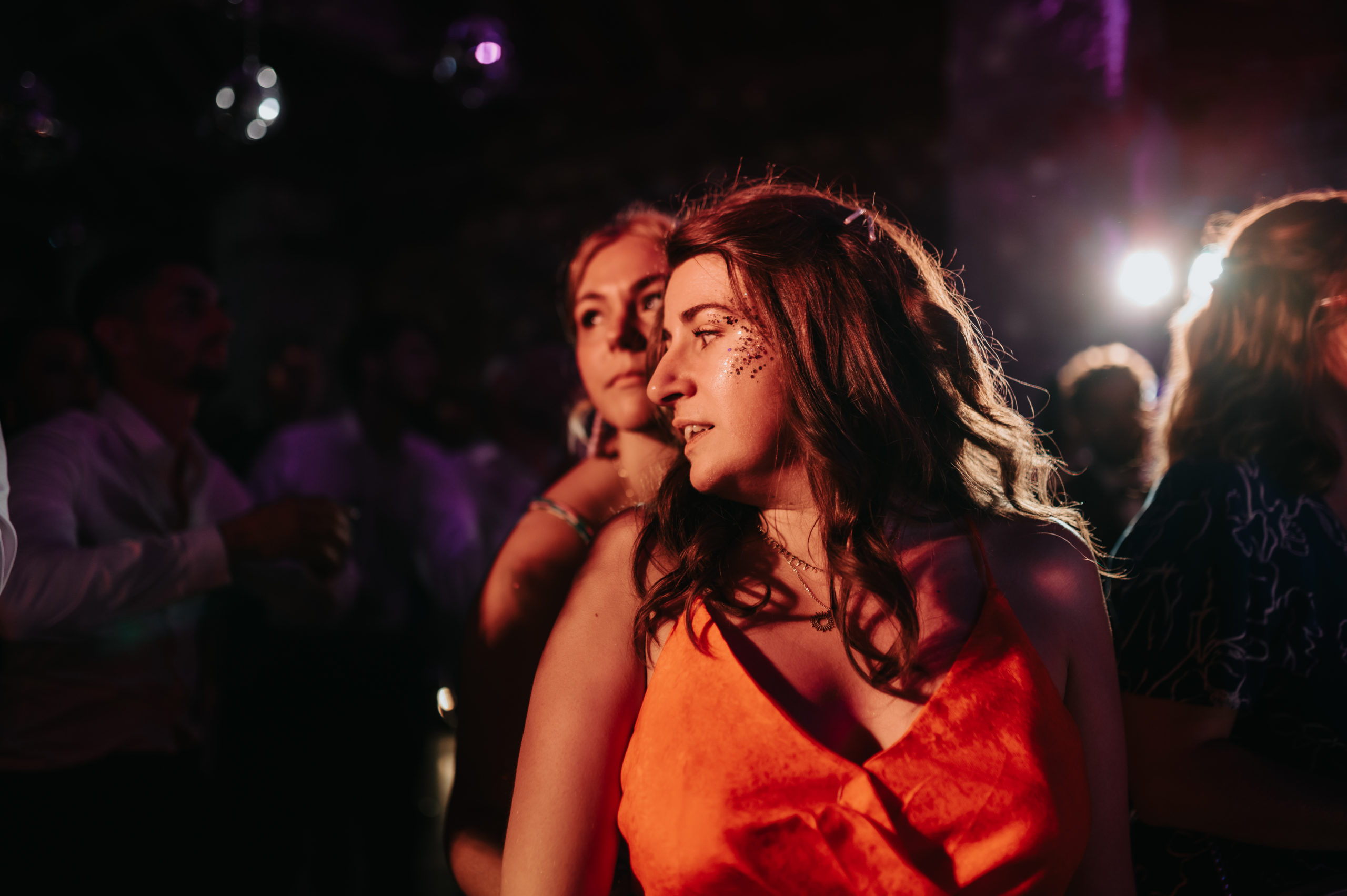 Une femme qui danse à un mariage avec des paillettes sur le visage.