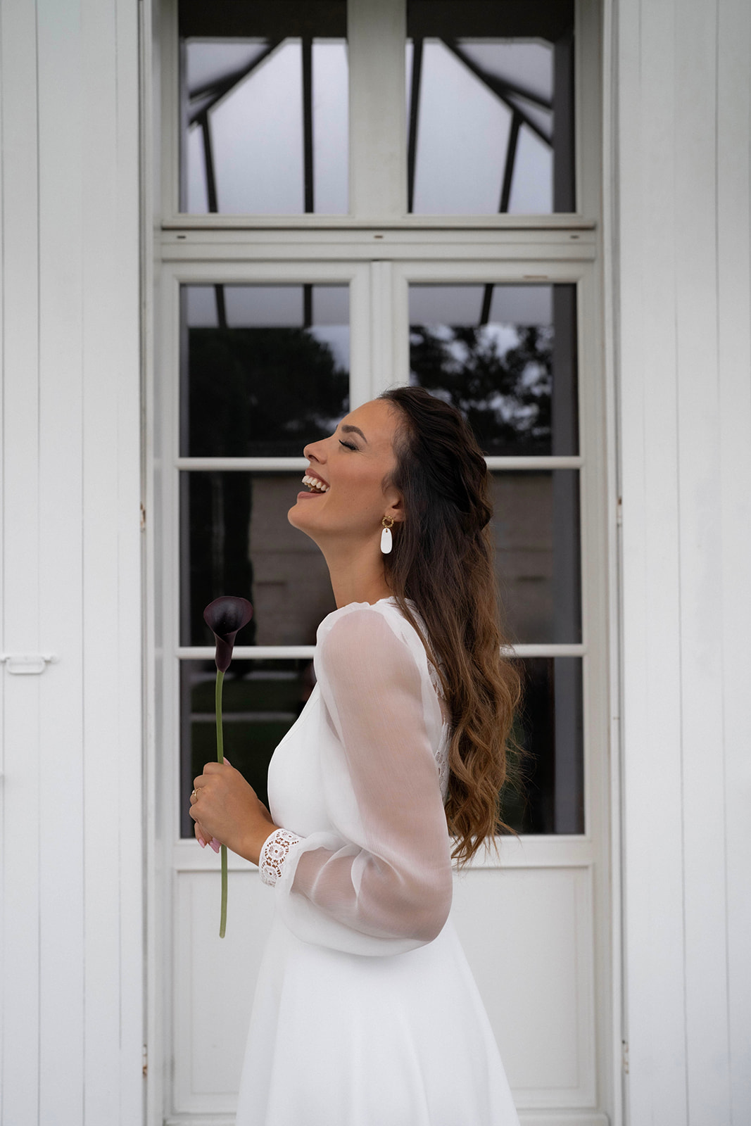 Une mariée chatain rit. Elle porte les cheveux détachés et un maquillage naturel mais sophistiqué.